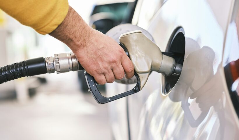Driver refuelling a car at a fuel station for a car fuel type comparison