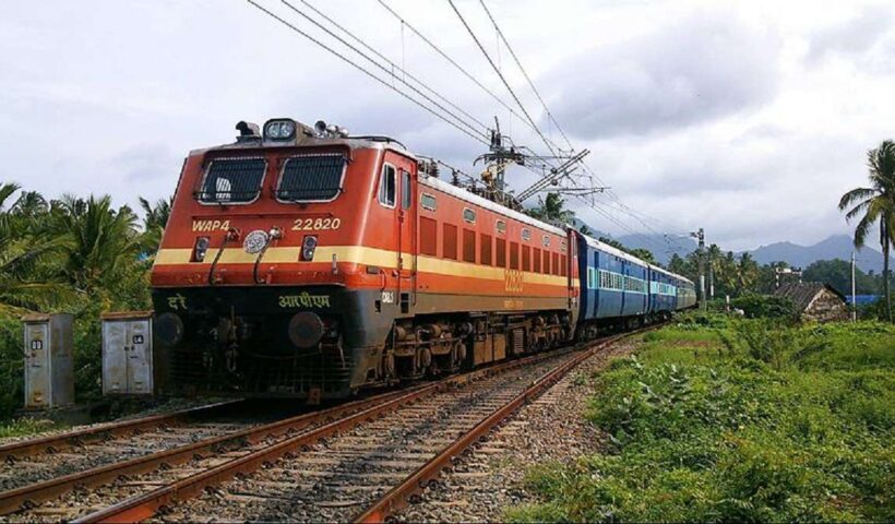 Indian Railways electric locomotive and passenger train on an electrified route.